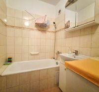 A bathroom with a shower and a sink in a 2-room apartment, tiled with light tiles.