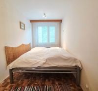 A bedroom in a 2-room apartment with a double bed and a wooden decor floor.