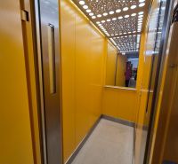 Elevator with bright yellow walls and a mirror.