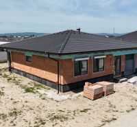 A family house in Bernolákovo with exposed bricks, a sloped roof, and an unkempt plot.