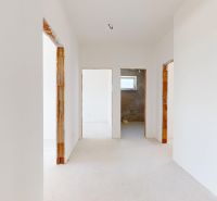 Hallway in a family house with white walls and a light wood-patterned floor.