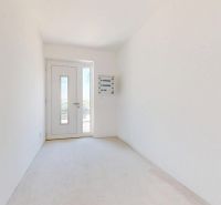 A spacious hallway in a family house with white walls and glass doors.