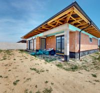 A family house in Bernolákovo in the stage of rough construction, surrounded by a sandy area.