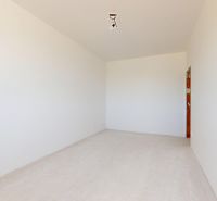 An empty room in a family house with white walls and no flooring.