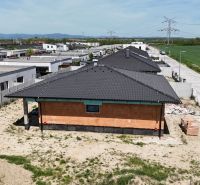 Construction site of family houses in Bernolákovo with modern roofs and an adjacent road.