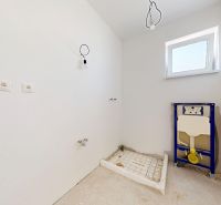 Unfinished bathroom in a family house with preparations for installations and a window on the wall.