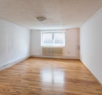 A room in a family house with a wooden decor floor and a central radiator.