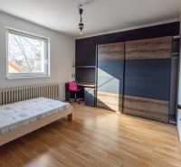 A room in a family house with a bed, a wardrobe, and a floor with a wooden decor.