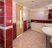 A bathroom with red tiles, a bathtub, and a double sink in a family house.
