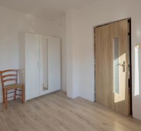 A room in a family house with a wooden decor floor, a wardrobe, and a chair.