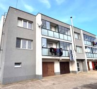 A three-story apartment building with balconies and cars in Hlboké.