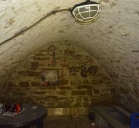 A stone cellar in a family house with a vaulted ceiling and small decoration.