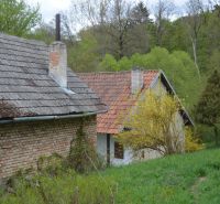 A family house in Bukovec with an old brick wall surrounded by a green environment and trees.