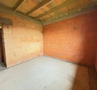 The interior of an unfinished family house with brick walls and a concrete floor.