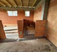 The interior of a family house under construction with a view of bricks and the ceiling.