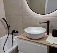 A bathroom in a 3-room apartment with a round mirror and modern faucets.