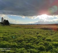 Extensive green lands, ideal for living, under the sun behind the clouds.