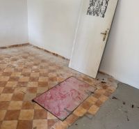 A room in a cottage with a tiled floor and doors without hinges.