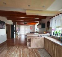 A kitchen with a wood-patterned floor, wooden beams, and decorations in a family house.