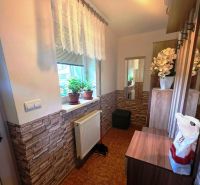 A compact hallway in a family house with brick cladding and flowers on the windowsill.