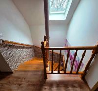 A staircase with a wooden decor, floral wallpaper, and a skylight in a family house.