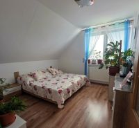 A bedroom in a family house with a wooden decor floor and a bed with a floral bedspread.