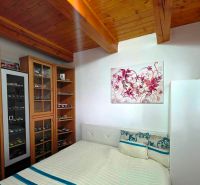 A bedroom in a family house with a showcase for model cars and a wooden ceiling.
