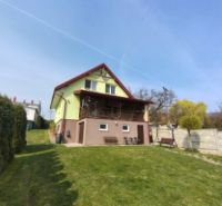 A family house in Klokočov with a grassy garden and a terrace on a sloped plot.