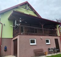 A family house in Klokočov with a covered terrace, greenery, and outdoor furniture.