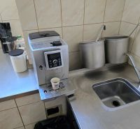 Kitchen corner with a coffee machine, stainless steel sink, and supplies in the catering area.