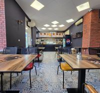 Gastro premises with a wooden decor floor and brick wall cladding.