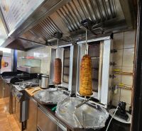 A kitchen in a gastro space with equipment for preparing kebab, including a range hood.