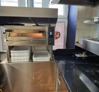 Gastro premises with a pizza oven, stainless steel counter, and ingredient containers.