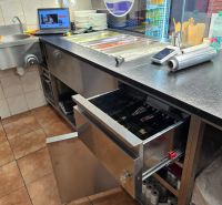 A kitchen unit in a gastro area with stainless steel equipment and a cash register.