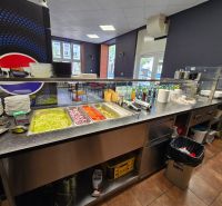 Gastro premises with bowls, vegetables, and drinks on counters and a floor with a wooden decor.