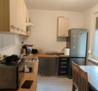 Kitchen in a 2-room apartment with appliances, a dining table, and large windows.