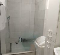Bathroom in a 2-room apartment with a spacious shower and white furniture.