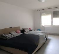Bedroom in a two-room apartment with a large window and a bed.
