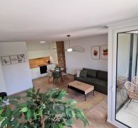 Interior of a 2-room apartment with a wood-decor floor, modern furniture, and a balcony.