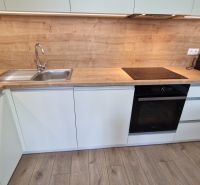 A kitchen with a wooden decor countertop and built-in appliances in a 2-room apartment.
