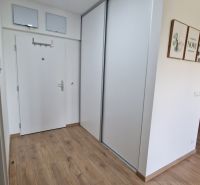 Interior of a 2-room apartment with a wooden decor floor, white doors, and a dining area.
