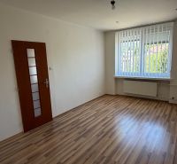A room in a one-room apartment with a wooden decor floor and a large window.
