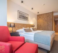 Recreational apartment with a double bed, red armchair, and built-in wardrobe.