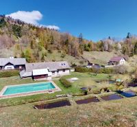 The exterior of a family house in Hnilčík with a swimming pool, trees, and hilly landscape.