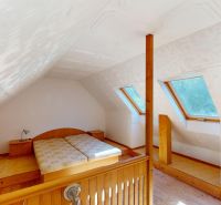 Attic bedroom in a family house with skylights and a wooden decor floor.