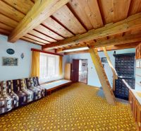 Interior of a family house with a patterned carpet, wooden ceiling, and decorative furniture.