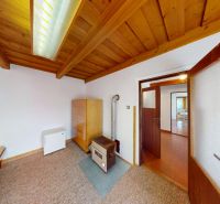 A room in a family house with roof beams, heating, and a dresser on the carpet.