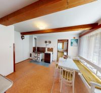 A dining room with wooden ceiling beams and tiles in a family house.