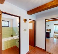 A hallway in a family house with a view into the bathroom and kitchen, wooden decor flooring.