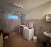 Bathroom with sink, washing machine, and shower in a family house.